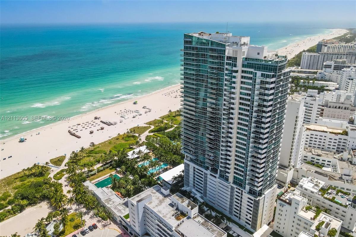 High-rise residential tower featuring glass-paneled balconies and direct proximity to the coastline