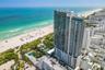 High-rise residential tower featuring glass-paneled balconies and direct proximity to the coastline