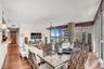 Open-concept interior featuring floor-to-ceiling windows, wood-finish flooring, a textured stone-clad support column, and custom chandelier lighting