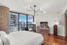 Floor-to-ceiling glass doors, natural stone-clad pillar, wood-finish flooring, and modern multi-arm chandelier
