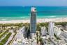 High-rise residential tower featuring a glass facade, multiple balconies, and an oceanfront location