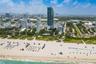 High-rise residential tower featuring a glass facade, oceanfront proximity, and expansive coastal shoreline
