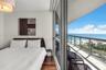 Floor-to-ceiling sliding glass doors, private balcony with metal and glass railing, wood-finish flooring, and recessed ceiling lighting