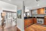 Kitchen featuring wood-finish cabinetry, dark stone-surface countertops, built-in oven, and recessed lighting, complemented by wood-finish flooring th