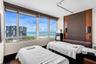 Floor-to-ceiling windows, wood-panel accent wall with built-in wall sconces, wood-finish flooring, and coastal scenery