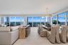 Expansive open floor plan featuring floor-to-ceiling glass walls, wood-finish flooring, recessed lighting, and a multi-globe branching chandelier