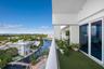 Covered outdoor balcony featuring synthetic turf surfacing, a solid white structural railing, and multi-panel floor-to-ceiling glass sliding doors