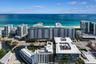 Aerial perspective of coastal high-rise property featuring balconies, rooftop pools, and water frontage