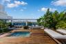 Rooftop terrace featuring wood-finish decking, an integrated in-ground spa, glass perimeter railing, and concrete planter boxes