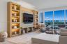 Custom light-wood built-in cabinetry with integrated accent lighting, floor-to-ceiling windows, and wood-finish flooring