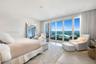 Floor-to-ceiling glass sliding doors, private balcony with metal railing, recessed ceiling lighting, and light-toned wood-finish flooring