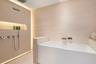 Freestanding deep-soaking bathtub with wall-mounted waterfall filler, integrated stone-finish wall cladding, recessed wall niche, concealed perimeter 