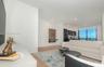 Open-concept interior featuring light wood-finish flooring, recessed lighting, and floor-to-ceiling windows with a distant skyline horizon