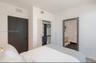 Neutral-toned bedroom featuring a dark solid-core door, built-in closet with integrated shelving, and a doorway showcasing a vanity with a light-finis
