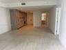 Open-plan living area featuring wood-finish cabinetry, stone-patterned backsplash, recessed lighting, and tile flooring
