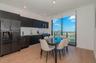 Modern kitchen featuring matte black flat-panel cabinetry, white horizontal tile backsplash, stainless steel appliances, wood-finish flooring, and flo