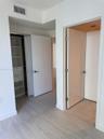 Interior space featuring wood-finish flooring, white solid-core doors with brushed nickel hardware, and built-in closet storage with integrated shelvi