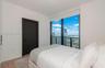 Floor-to-ceiling windows with expansive urban cityscape scenery, dark-finish interior door, recessed lighting, and light-tone wood-finish flooring