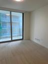 Floor-to-ceiling sliding glass door, private balcony with glass railing, and wood-finish flooring