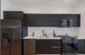 Modern kitchen featuring flat-panel cabinetry, a white subway tile backsplash, light-toned countertops, a stainless steel undermount sink, and matte b