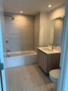 Bathroom featuring a floating vanity with wood-finish cabinetry, a white countertop with an integrated sink, a rectangular wall-mounted mirror, floor-