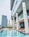 Outdoor swimming pool featuring a concrete deck, floor-to-ceiling glass building facade, and prominent structural columns