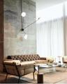 Exposed concrete accent wall with floor-to-ceiling height, multi-arm wall-mounted light fixture with globe bulbs, and full-height window drapery