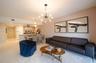 Open-concept living space featuring wood-finish flooring, a multi-arm sputnik-style chandelier, neutral wall tones, and a kitchen peninsula with integ