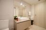 Modern floating vanity with a rectangular vessel sink and wall-mounted faucet, oversized wall mirror, light-toned wood-finish door, and neutral tile f