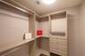 Walk-in closet featuring light wood-finish shelving, integrated hanging rods, and a four-drawer built-in cabinet unit with metallic pulls