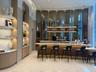 Bar area featuring a stone-topped counter, reeded wood-finish base, integrated lighting, stone shelving, and a mirrored paneled wall