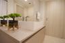 Modern vanity featuring a solid surface countertop, rectangular vessel sink, polished chrome faucet, louvered built-in cabinet doors, and light-toned 