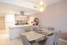 Kitchen featuring light-toned cabinetry, a peninsula with a solid-surface countertop, stainless steel range hood, and a geometric gold-tone pendant li
