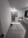 Bathroom featuring large-format tile flooring, a walk-in shower with a glass enclosure, a built-in soaking tub with tile surround, and a vanity with w