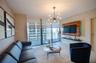 Floor-to-ceiling windows with integrated roller shades, wood-finished media wall with built-in shelving, multi-bulb modern sputnik chandelier, and til