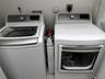 Top-loading washing machine and front-loading dryer with metallic-finish accents and digital control panels