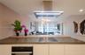 Kitchen peninsula featuring a stone countertop, built-in cooktop, and elevated wood-finish breakfast bar, complemented by a stainless steel ceiling-mo