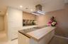 Kitchen featuring custom cabinetry with wood-finish and solid-color flat-panel doors, stone-composite countertops, integrated appliances, and a stainl