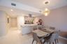 Kitchen featuring a stainless steel range hood, stone-finish countertops, flat-panel cabinetry, geometric pendant lighting, and neutral-tone tile floo