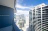 Curved balcony featuring tiled flooring, glass panel railing, and cityscape scenery