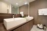 Floating wood-finish vanity with dual rectangular vessel sinks, polished chrome faucets, large frameless mirror, and walk-in shower with stone-finish 