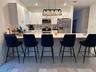 Kitchen featuring white cabinetry, solid-surface countertops with an integrated breakfast bar, stainless steel appliances, and rectangular-tile floori