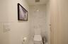 Powder room featuring a stone-finish tile accent wall, stone-finish flooring, dual-flush elongated toilet, and a light-toned wood-finish door