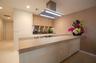 Modern kitchen featuring wood-finish cabinetry, sleek stainless steel backsplash, integrated cooktop, extended breakfast bar, and a stainless steel is