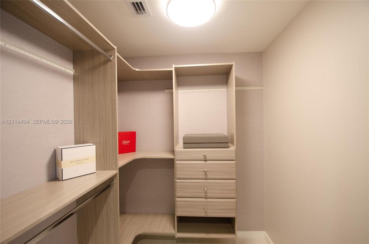 Custom storage system featuring wood-finish shelving, integrated hanging rods, and a four-drawer cabinetry unit with hardware