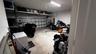 Garage interior featuring a sectional metal garage door, concrete flooring, and elevated wall-mounted steel shelving units