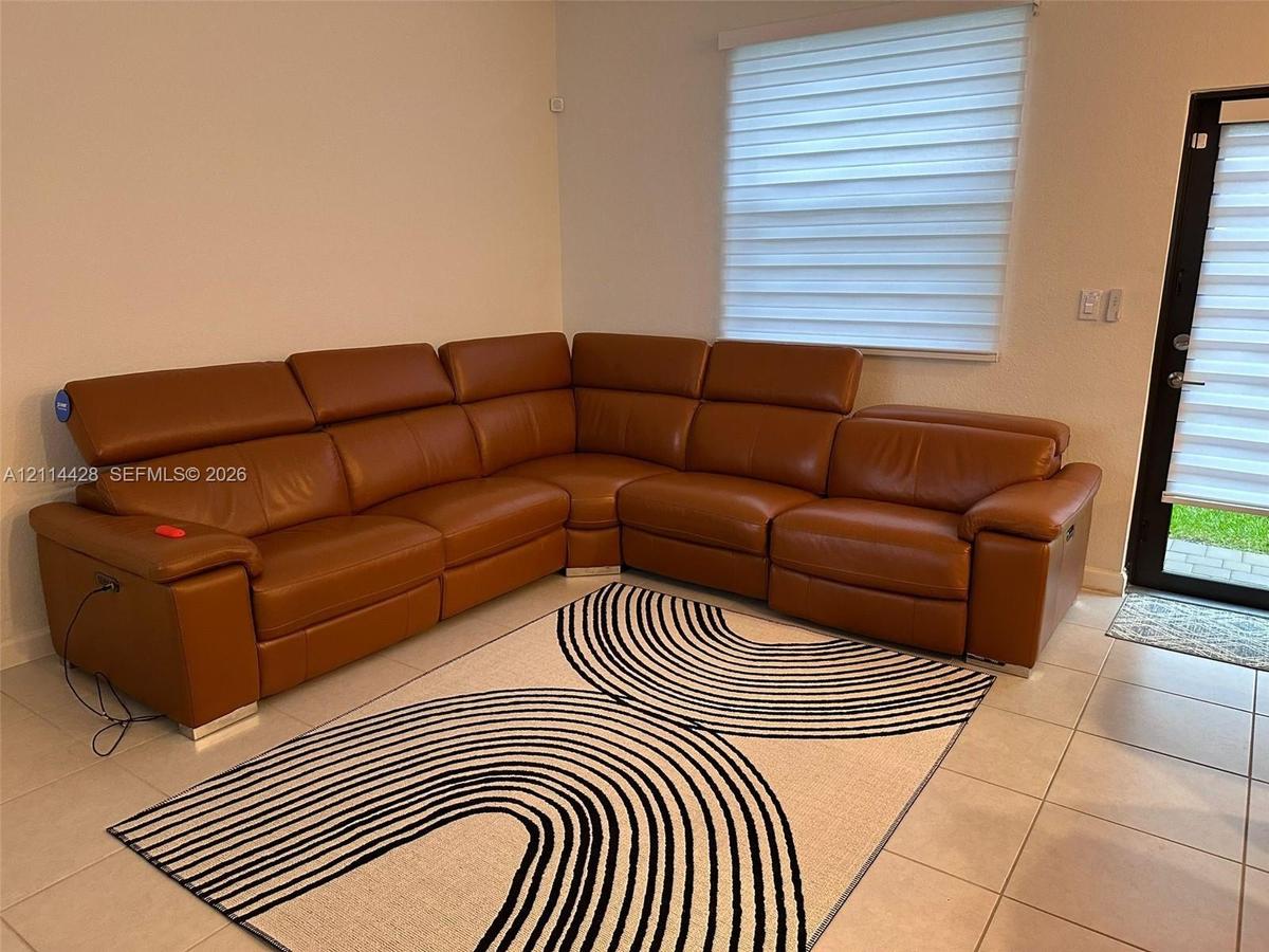 Neutral-toned tile flooring, light-filtering roller shades, and a glass-paneled exterior door
