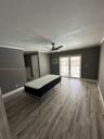 Wood-finish flooring, neutral wall tones, multi-light French doors, ceiling fan, and wall-mounted air conditioning unit