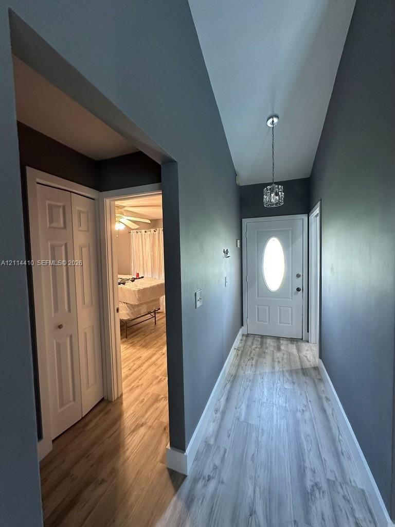 Entryway featuring wood-finish flooring, a white six-panel door with an oval glass insert, bi-fold closet doors, and a crystal-accented pendant light 