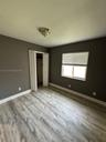 Room featuring wood-finish flooring, neutral-toned walls, a double-panel closet door, and a horizontal window with fitted blinds